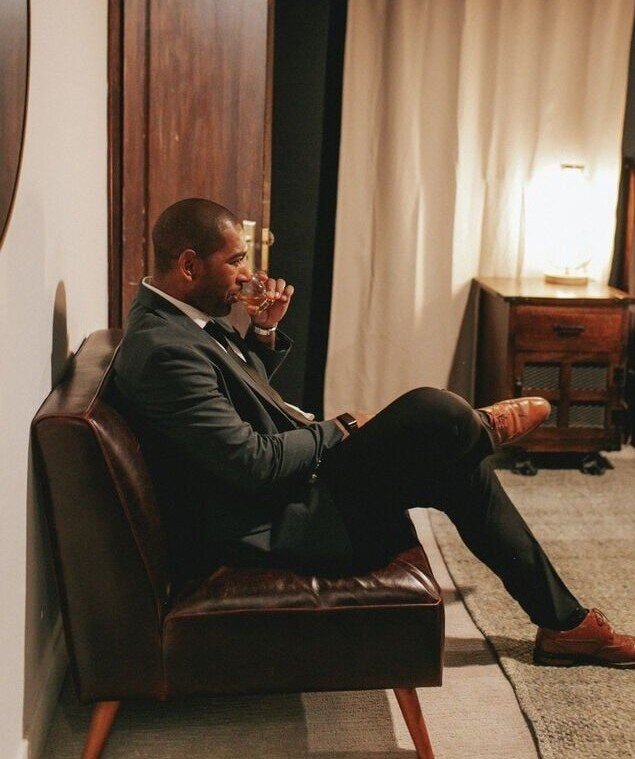 man sipping wine in a dim room